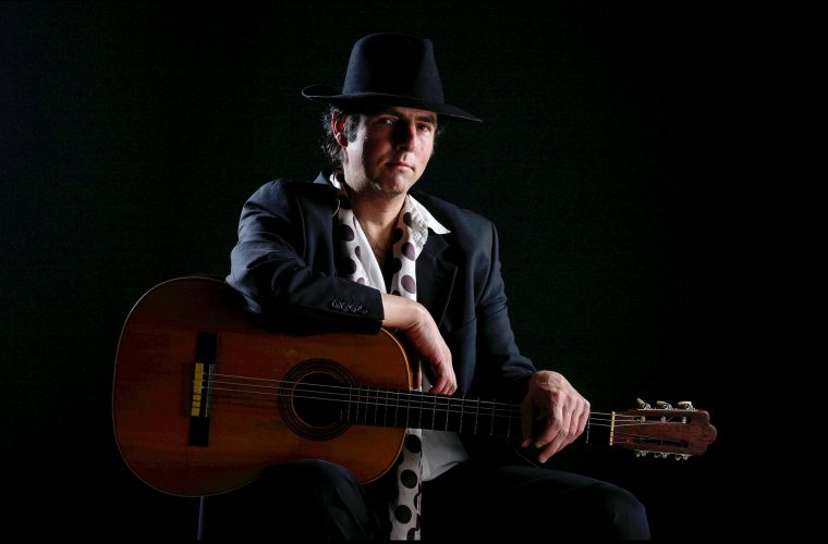 Gipsy flamencogitarist Manito met klassieke gitaar op zwarte achtergrond